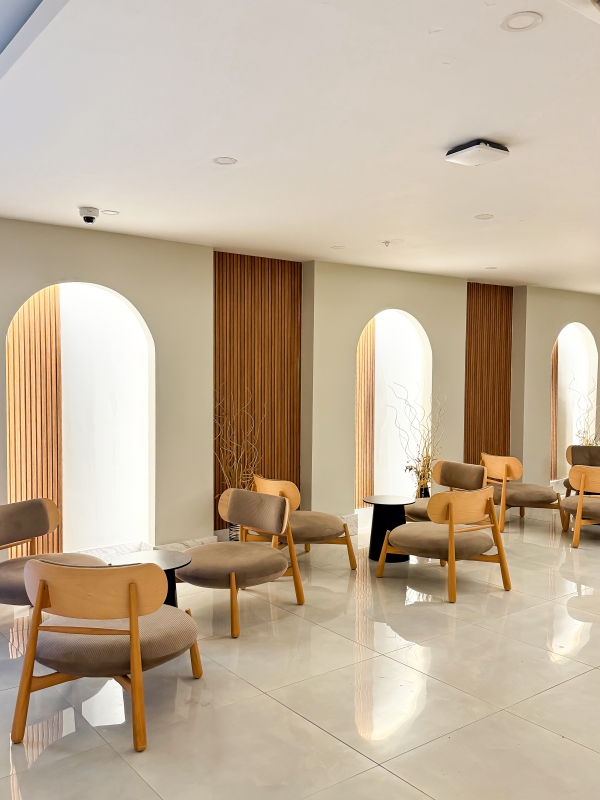 Minimalist Waiting Area Or Lounge With Wooden Armchairs, Arched Wall Niches, And Warm Recessed Lighting.